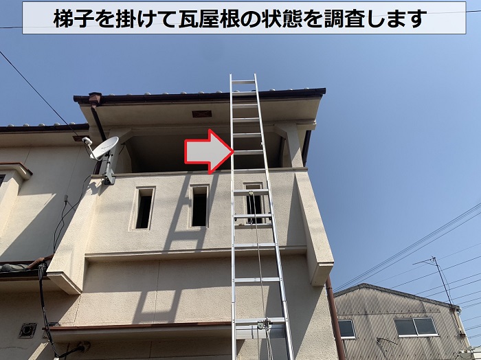 梯子を掛けて瓦屋根の状態を調査する様子