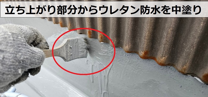 2階建てアパートのバルコニーの立ち上がり部分からウレタン防水を中塗りしている様子