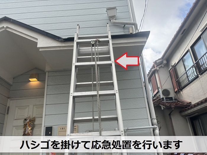 アパートにハシゴを掛けて雨樋の応急処置を実施