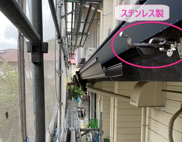 雨樋の部分取り替えで新しい雨樋のステンレス製の固定金具を取り付けている様子