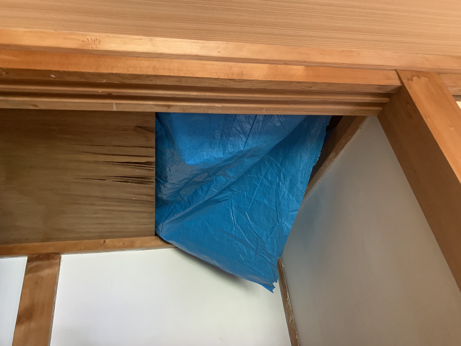 豪雨で雨漏りしてきた雨水をシートで養生している様子