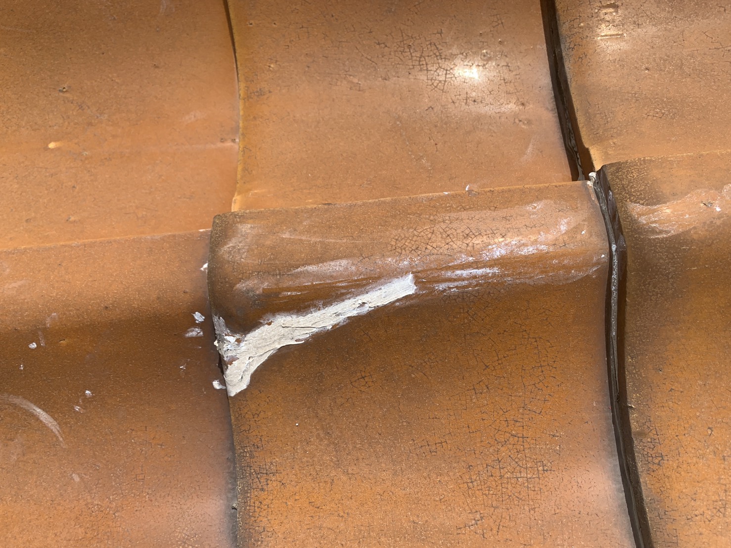 ひび割れた瓦をコーキングで補修している様子