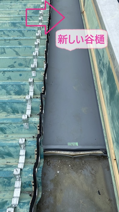 工場の88折板屋根に新しい谷樋を取り付けている様子