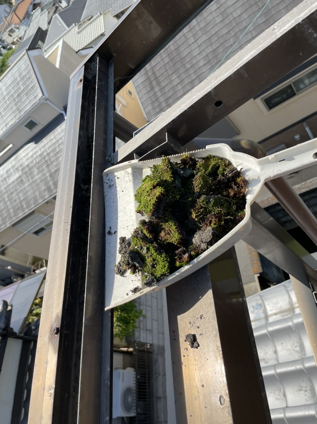 ベランダ屋根の雨樋を掃除している様子