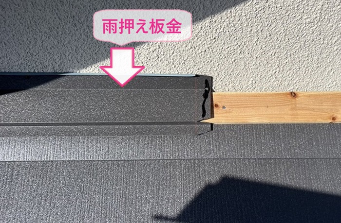 スレート屋根重ね葺き工事で壁際に雨押さえ板金を取り付けている様子