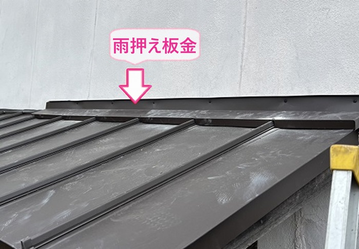 窓上の小庇の交換工事で壁際に雨押え板金を取り付けている様子
