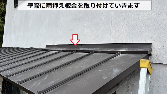 庇屋根の壁際に雨押え板金を取り付けている様子