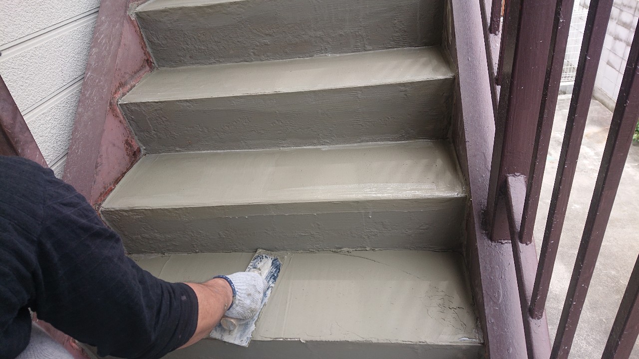 経年劣化した外部階段にセメントを塗っている様子