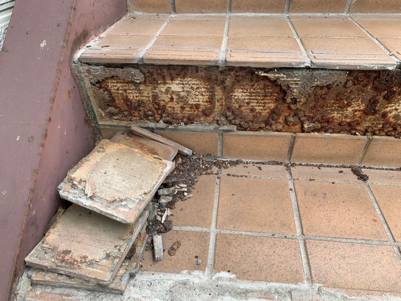 経年劣化で外部階段のタイルが剥がれている様子