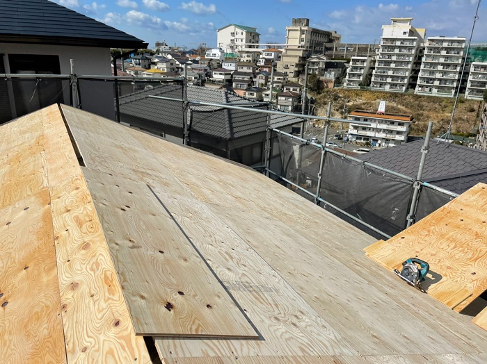 屋根に下地用合板を取り付けている様子