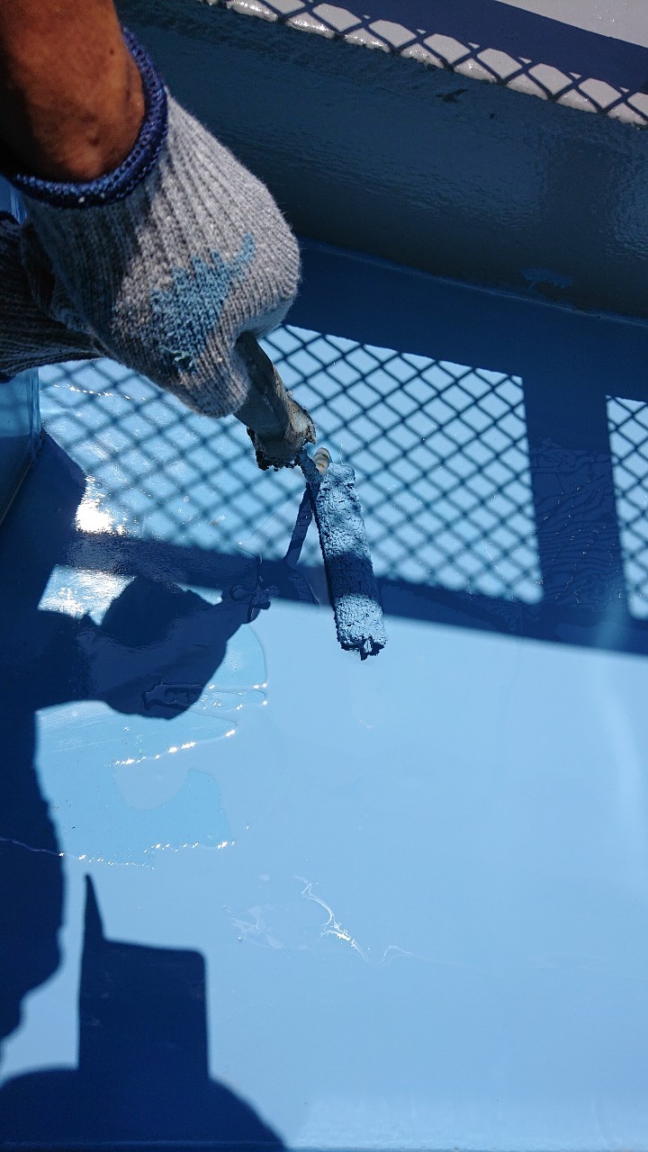 雨漏り修理でひび割れたベランダ床にウレタン防水を中塗りしている様子