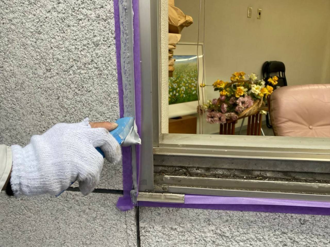 神戸市中央区でのコーキング打ち替え工事でサッシ廻りのコーキングを押えている様子