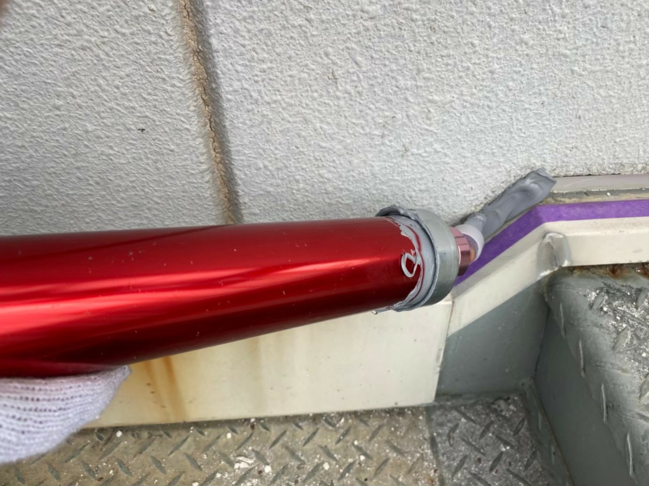 神戸市中央区でのコーキング打ち替え工事で鉄骨階段廻りにコーキングを打設している様子