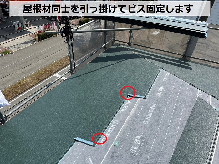 3階建てスレート屋根への重ね葺き工事で屋根材をビス止めしている様子