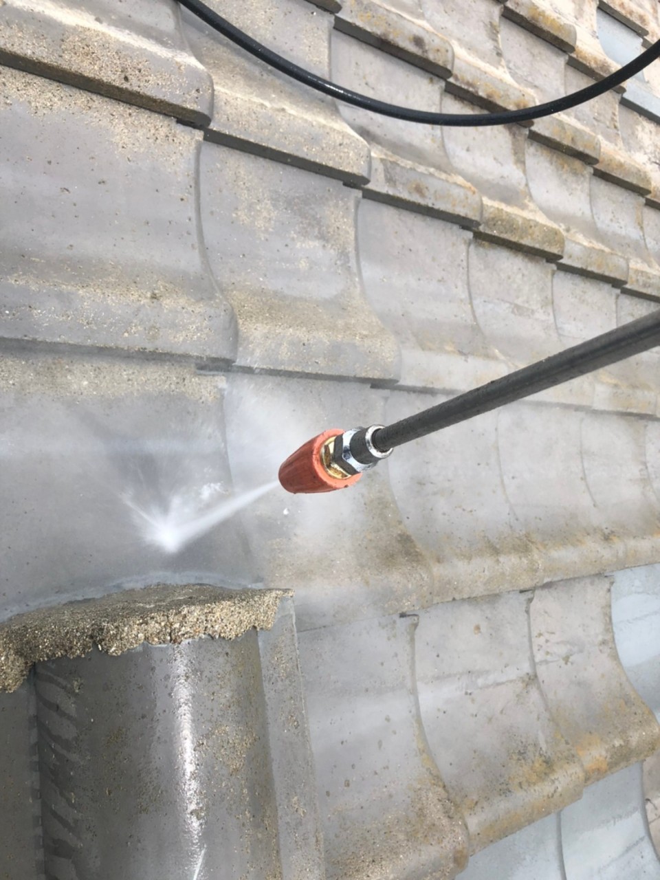 屋根塗装をするために高圧洗浄している様子