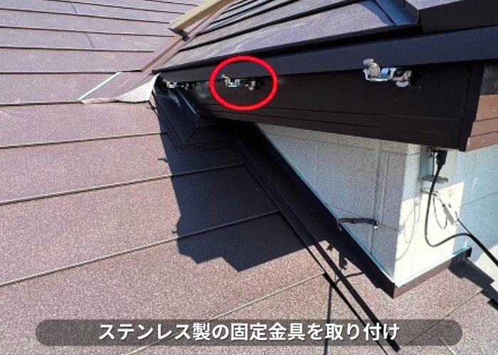 朝来市 雨樋交換でステンレス製の固定金具を取り付けている様子