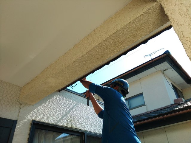 金づちで雨樋の金物の微調整を行っているところ