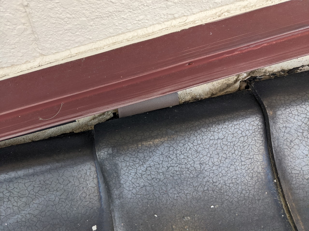 雨押え板金の下の瓦屋根の漆喰が割れている