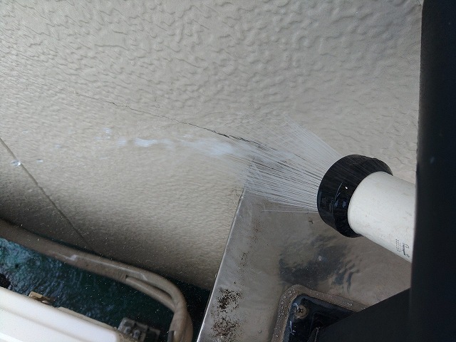 外壁の亀裂に散水試験を行っている状態