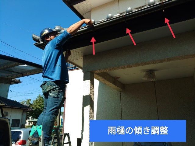 玄関上部の雨樋の金具の調整を行っているところ