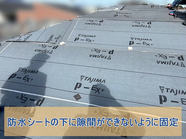 隙間や皺ができないように防水シートを固定する様子