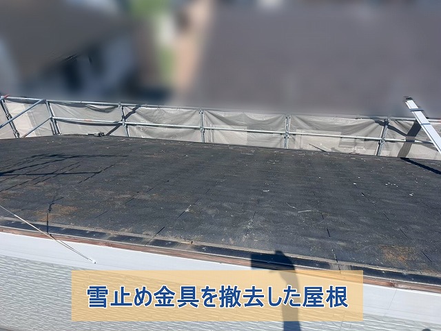 雪止め金具をスレート屋根から外している様子