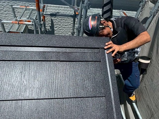 棟板金を取り付けている作業員