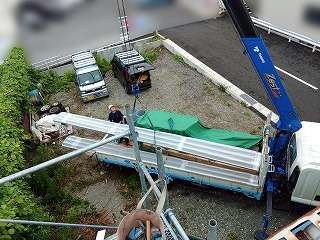 新しい屋根材をクレーンで運搬しているところ
