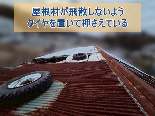 屋根材が飛散しないようにするためタイヤを置いて押さえている