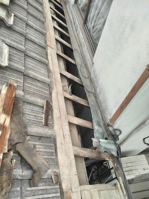 野地板撤去箇所の垂木と既存谷板金の一部が見える屋根の状態