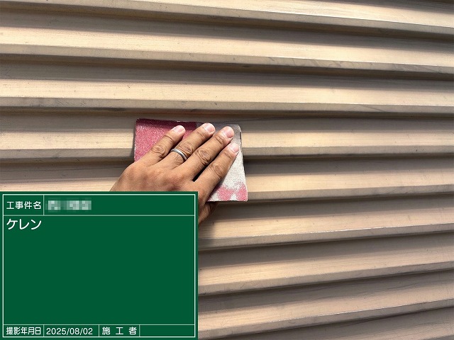 サンドペーパーで金属製の雨戸表面をケレンしている様子