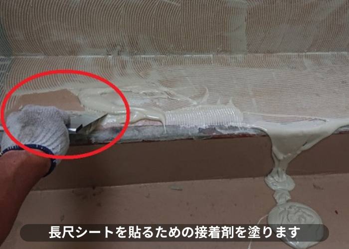 マンションの階段に長尺シートを貼るための接着剤を塗っている様子