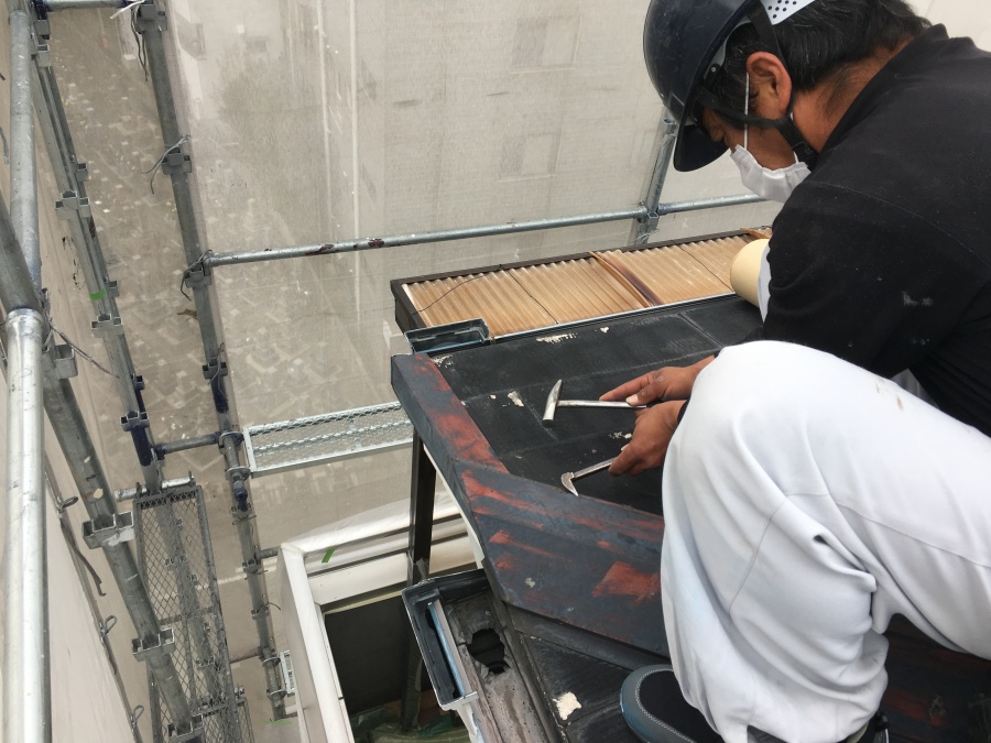 屋根の古い板金を撤去する職人