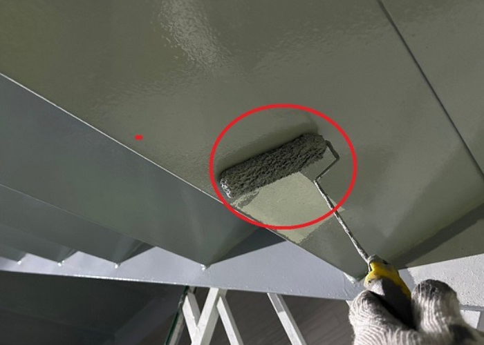 大阪市で3階建てアパートの部分塗装工事として鉄骨階段へ錆止め塗装する現場で上塗りを行っている様子