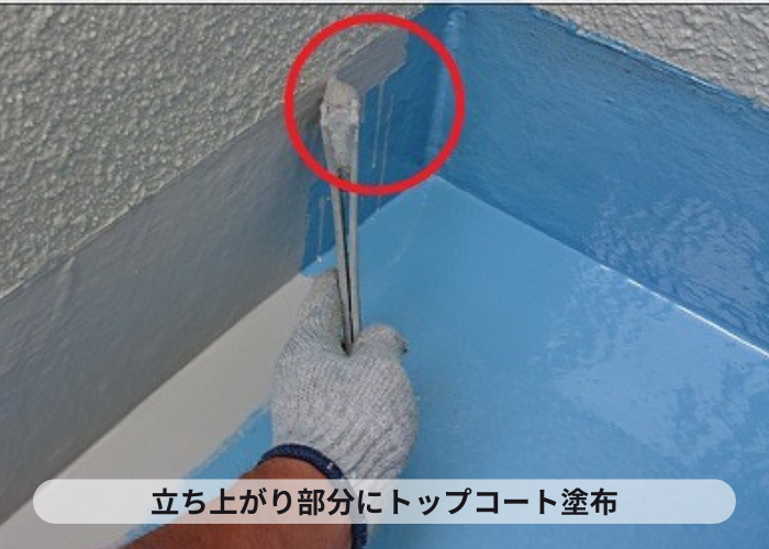 バルコニーへのウレタン防水工事でトップコートを立ち上がりに塗っている様子
