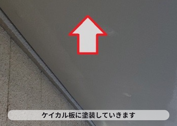 吹田市での軒天補修でケイカル板に塗装している様子