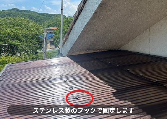 高槻市2階ベランダ屋根の貼り替えで波板をステンレス製のフックで固定している様子