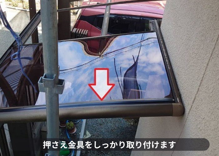 サイクルポート屋根に押さえ金具を取り付けている様子