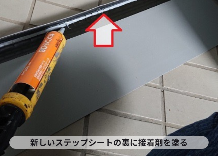 共用階段の部分補修で新しいステップシートの裏に接着剤を塗っている様子
