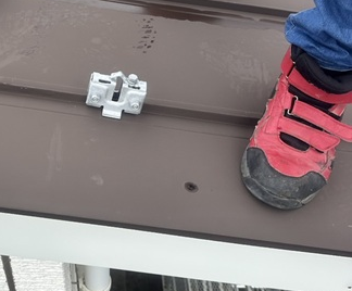 まずはじめに、立平葺き屋根の凸部分に、雪止めアングルの金具を挟んでナットで締めます。