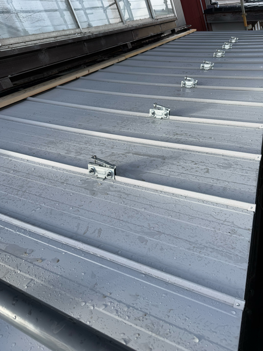 立平葺き屋根の凸部分に、雪止めアングルの金具を挟んでナットで締めます。